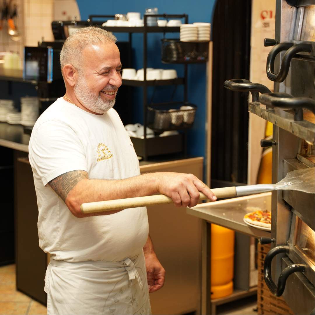 Medarbejder fra Coccobelle i Randers sætter pizza i stenovn. 